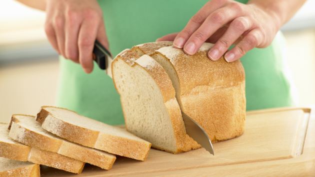 Woman Slicing A Loaf Of White Bread